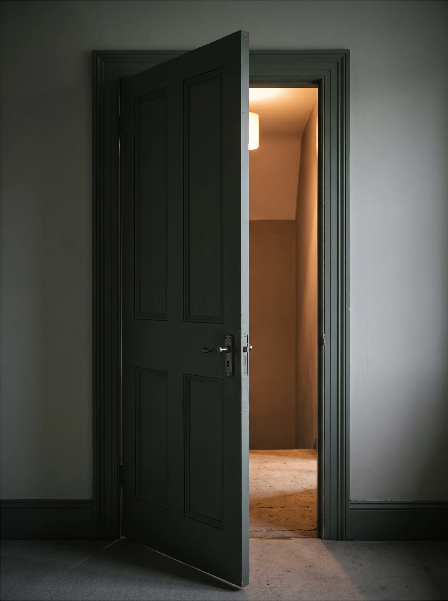 The room's door standing ajar, seen from inside, with daylight from the landing beyond